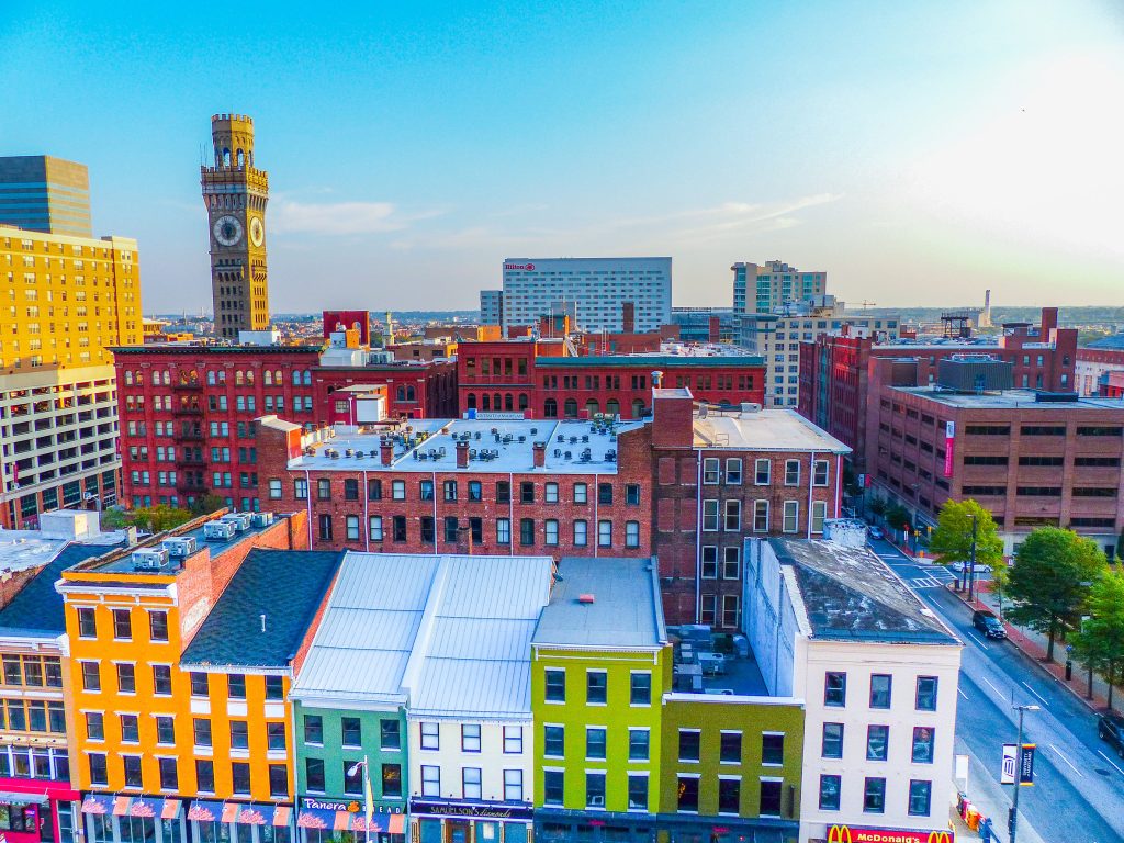The view of Baltimore City with brightly colored rowhomes in the foreground.