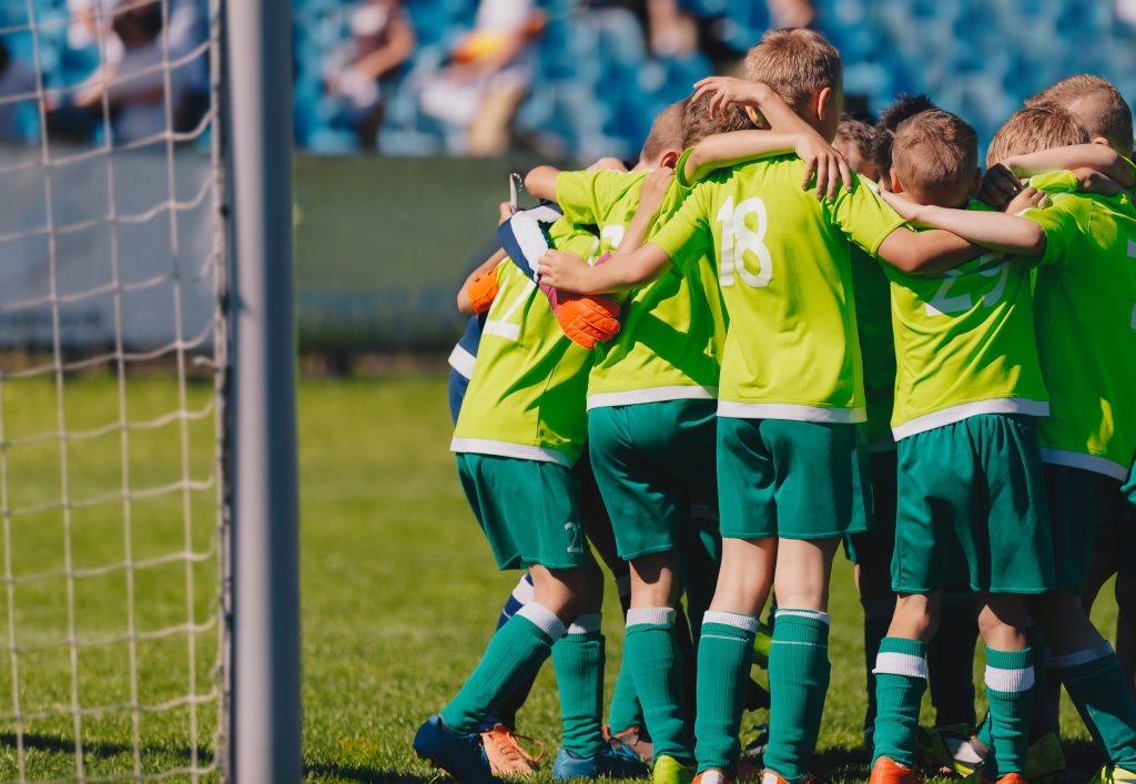Team Sport: Children's Soccer Team Hugging on the Field